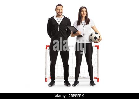 Full length portrait of a male and female football coaches posing in front of mini goal isolated on white background Stock Photo