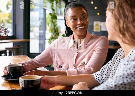 Two Young Female Friends Meeting In Coffee Shop And Talking Stock Photo