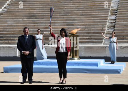 200320 -- BEIJING, March 20, 2020 -- President of the Hellenic Olympic Commitee Spyros Capralos L passes the Tokyo Olympic flame to Imoto Naoko, an Olympian in swimming at the Olympic Games of Atlanta 1996, at the Panathenaic stadium, in Athens, Greece, on March 19, 2020. Photo by -pool photo/Xinhua XINHUA PHOTOS OF THE DAY ARISxMESSINIS PUBLICATIONxNOTxINxCHN Stock Photo