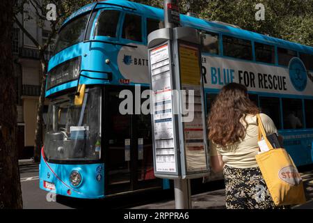 A woman traveller waits for her next service at a bus stop at Aldwych in the West End, on 5th September 2023, in London, England. Stock Photo