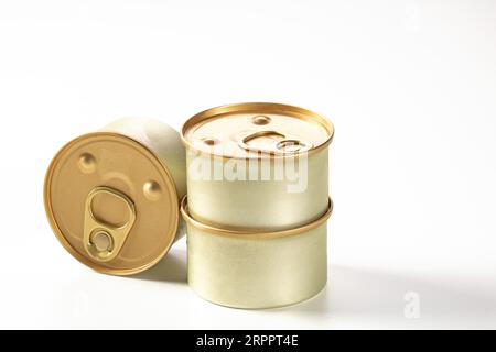 Three metal cans of cat food on a white background. Drops of condensate are visible on the cans, they have just been taken out of the refrigerator Stock Photo