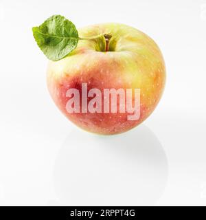 One apple with a red side and a green leaf on a white background. Stock Photo