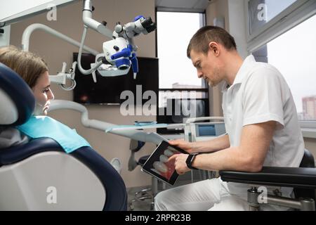 Dentist communicates with patient in dental office. Stock Photo