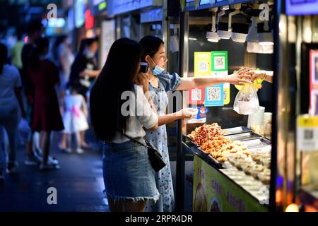 200326 -- HAIKOU, March 26, 2020 -- People buy food at a snack street in Haikou, capital of south China s Hainan Province, March 26, 2020. South China s island province of Hainan on Tuesday reduced its existing number of cases of novel coronavirus disease COVID-19 to zero. People s life here is gradually returning to normal.  CHINA-HAINAN-HAIKOU-LIFE-BACK TO NORMAL CN GuoxCheng PUBLICATIONxNOTxINxCHN Stock Photo