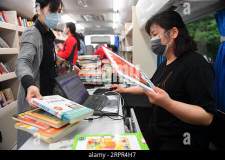 200326 -- CHANGSHA, March 26, 2020 -- A woman borrows books in a mobile library in a community of Changsha, central China s Hunan province, March 26, 2020. Recently, the mobile libraries in Changsha have resumed operation amid epidemic prevention and control measures. Mobile library is a project of Changsha Library which takes buses as carriers to visit communities, schools, companies, construction sites and other areas in the city monthly and provide book reading, consulting, borrowing and returning services.  CHINA-HUNAN-CHANGSHA-MOBILE LIBRARY CN ChenxZeguo PUBLICATIONxNOTxINxCHN Stock Photo