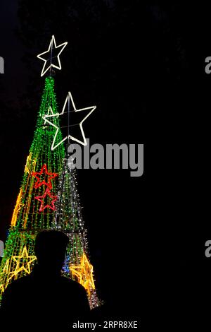 Backlit silhouette of a person on the street in front of Christmas decorations at night Stock Photo