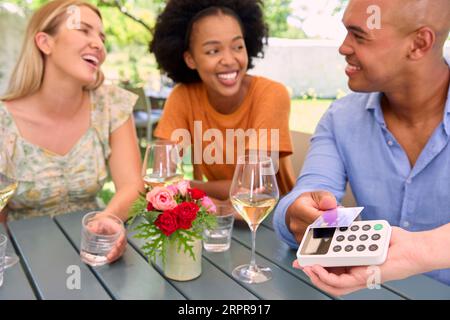 Close Up Of Man Making Contactless Payment At Outdoor Bar Or Restaurant Using Credit Or Debit Card Stock Photo