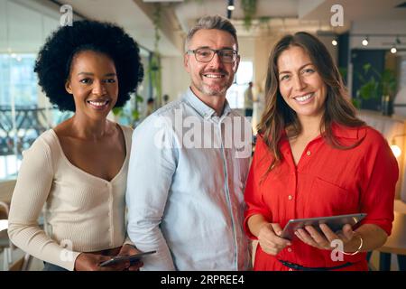 Portrait Of Multi-Cultural Business Team With Digital Tablet In Busy Office Stock Photo