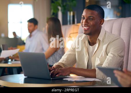 Businessman Working On Laptop In Informal Seating Area Of Modern Office Stock Photo