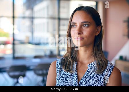 Portrait Of Young Businesswoman With Serious Expression Standing In Empty Office Stock Photo