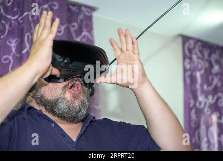 Overweight man with beard amazed while contemplating virtual reality at VR Stock Photo