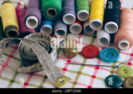 Sewing kit consisting needle, thimble, threads and measuring meter on a fabric background Stock Photo