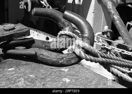 Large iron grappling hooks and thick ropes ropes on the boardwalks secure the fishing trawlers in Plymouth's busy harbour Stock Photo