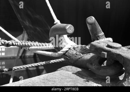Large iron grappling hooks and thick ropes ropes on the boardwalks secure the fishing trawlers in Plymouth's busy harbour Stock Photo