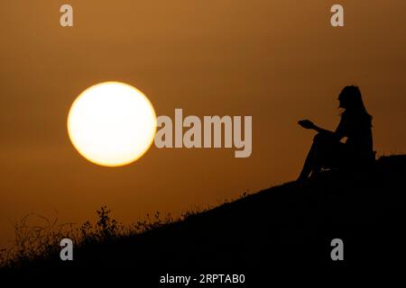 London, UK.  5 September 2023.  UK Weather – A woman enjoys the sunset atop the man-made mounds of Northala Fields in Northolt, west London.  The UK Health Security Agency has issued an amber alert saying that people of all ages could be affected by the current heatwave as the Met Office predicts high temperatures exceeding 30C for the week.  Credit: Stephen Chung / Alamy Live News Stock Photo