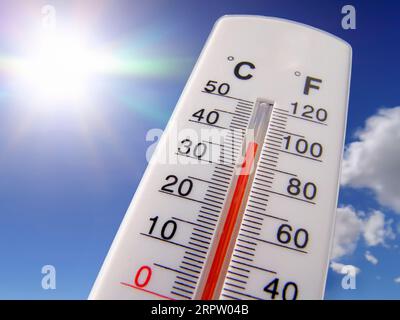 Thermometer sunburst 38C HEATWAVE HOT 100F Temperature gauge rising red Concept Sky Thermometer displays hot & sunny 38C centigrade 100F degrees farenheit against a bright blue sky Climate change Global warming concept Stock Photo