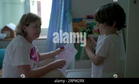 Child interacting with grandmother in bedroom. Candid authentic grandma's relationship with her grandson Stock Photo