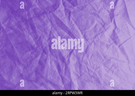 Wrinkled, crumpled purple fabric texture background. Wrinkled and creased abstract backdrop of spunbond  textile, wallpaper with copy space, top view. Stock Photo