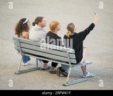 Four people on a bench taking a selfie Stock Photo
