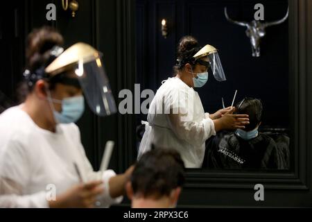 200505 -- LISBON, May 5, 2020 Xinhua -- A hairdresser wearing a face mask cuts the hair of a client at a hairdressing salon in Lisbon, Portugal, May 4, 2020. Portugal started to revive its economy and society on Monday after nearly 50 days of lockdown under the state of emergency due to the COVID-19 pandemic. During the phase one of the three-step deconfinement from Monday to May 18, commercial centers up to 200 square meters and street stores are allowed to reopen with strict sanitary measures. Photo by Pedro Fiuza/Xinhua PORTUGAL-LISBON-COVID-19-REOPENING-PHASE ONE PUBLICATIONxNOTxINxCHN Stock Photo