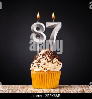 Birthday candle number 87 - Anniversary cupcake on black background Stock Photo