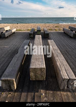 Slabs of timber serving as seating outside the East Beach Cafe in Littlehampton, West Sussex, UK. showing the beach behind and sea Stock Photo