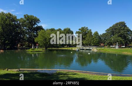 Sculptures on Schiller Pond--on a small island and suspended above the water--and a fountain add points of interest to Schiller Park in German Village. Stock Photo