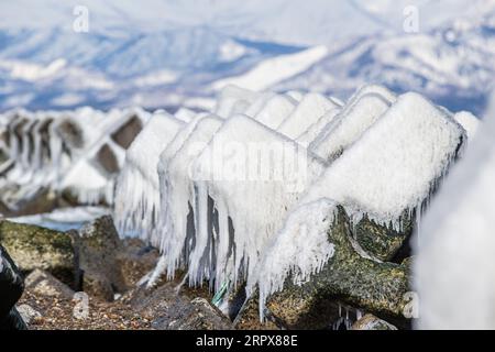Ice covered concrete blocks as waves breakers on the Japanese beach in winter time. Hokkaido Island, Japan Stock Photo