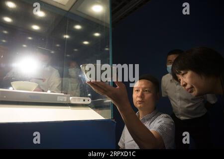 200517 -- HANGZHOU, May 17, 2020 -- Liu Jie front L shows his replica of Bakohan at the Zhejiang Provincial Museum in Hangzhou, east China s Zhejiang Province, May 15, 2020. Liu Jie, 35 and a renowned ceramist in Longquan, began to replicate Bakohan since 2019. He has so far made over 500 replicas in an effort to approach perfection. I wish to replicate its beauty. said Liu. Bakohan is a tea bowl made in Longquan, China, and gifted to Japan during the Southern Song Dynasty 1127-1279. During the era of Ming Dynasty 1368-1644, Bakouhan was found to have cracks and was then sent to China to be fi Stock Photo