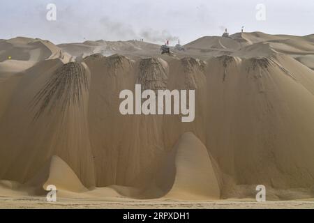 200518 -- YULI, May 18, 2020 -- Workers drive bulldozers at the construction site of a highway in Taklimakan Desert, northwest China s Xinjiang Uygur Autonomous Region, May 16, 2020. The construction of Yuli-Qiemo highway, the third north-south route running through Taklimakan Desert, has entered the final rush. Workers of China Communications Construction Company Ltd. are working on the largest dune in this project, with an estimated volume of 1.2 million cubic meters of sand to deal with. They established camps next to the dune for the convenience of work, and receive daily necessities on a Stock Photo