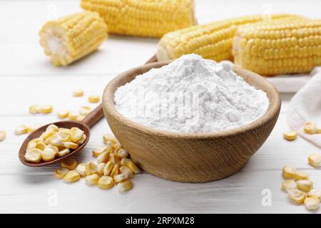 Bowl with corn starch and kernels on white table Stock Photo