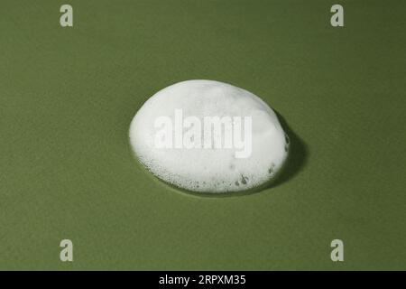 Sample of cleansing foam on dark green background, closeup. Cosmetic product Stock Photo