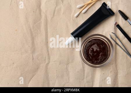 Flat lay composition with eyebrow henna and tools on crumpled paper. Space for text Stock Photo
