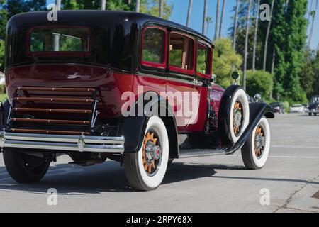 Packard automobile, with wooden-spoke wheels, shown driving in a residential area. Stock Photo