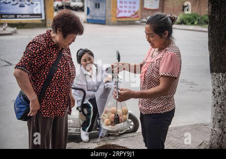 200621 -- ANKANG, June 21, 2020 -- Li Zengyi s wife Tang Guoqun 1st R and their daughter Li Dan C sell peaches at a market in Ankang City, northwest China s Shaanxi Province, June 19, 2020. In 1997, in order to shake off poverty, Li Zengyi, a villager in Wenhua Village of Ankang City, moved his family, including his seven-year-old disabled daughter, to a makeshift house on a mountain to cultivate peaches. Li Wei, the elder son of Li Zengyi, went out to work in south China s Guangdong Province after graduation from middle school to support the family. Li Peng, the younger son, continued his stu Stock Photo