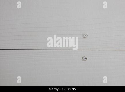 Screw fixing on white synthetic wood flooring Stock Photo
