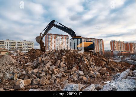 Excavator pours soil on pile of garbage at demolition site Stock Photo