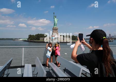 200720 -- NEW YORK, July 20, 2020 -- Visitors pose for photos with the Statue of Liberty on the cruise to Liberty Island in New York, the United States, July 20, 2020. New York City entered phase four of reopening on Monday without resuming additional indoor activities, as local officials are concerned about a potential second wave of coronavirus infections brought here from new hotspots across the country. The Liberty Island where the Statue of Liberty is located became open on Monday, while the interior of the statue and the museum remain closed to the public.  U.S.-NEW YORK-COVID-19-PHASE F Stock Photo