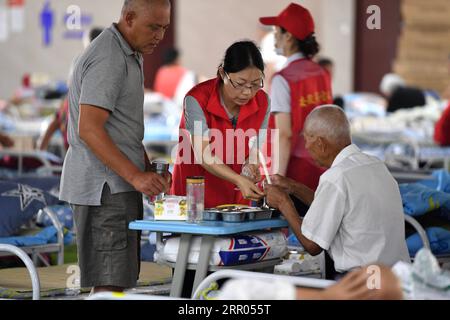 200729 -- HEFEI, July 29, 2020 -- A volunteer distributes a box meal to a villager at a temporary shelter in the No.168 Middle School in Hefei, east China s Anhui Province, July 29, 2020. Affected by floods, more than 300 villagers in Sanhe Town of Hefei were transferred to the school. Free meals, psychological counseling and daily living assistance are provided in the shelter.  CHINA-ANHUI-HEFEI-FLOOD-TEMPORARY SHELTER CN LiuxJunxi PUBLICATIONxNOTxINxCHN Stock Photo