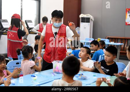 200729 -- HEFEI, July 29, 2020 -- A volunteer plays games with children at a temporary shelter in the No.168 Middle School in Hefei, east China s Anhui Province, July 29, 2020. Affected by floods, more than 300 villagers in Sanhe Town of Hefei were transferred to the school. Free meals, psychological counseling and daily living assistance are provided in the shelter.  CHINA-ANHUI-HEFEI-FLOOD-TEMPORARY SHELTER CN LiuxJunxi PUBLICATIONxNOTxINxCHN Stock Photo