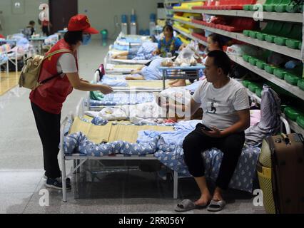 200729 -- HEFEI, July 29, 2020 -- A volunteer gives a safety instruction booklet to a villager at a temporary shelter in the No.168 Middle School in Hefei, east China s Anhui Province, July 29, 2020. Affected by floods, more than 300 villagers in Sanhe Town of Hefei were transferred to the school. Free meals, psychological counseling and daily living assistance are provided in the shelter.  CHINA-ANHUI-HEFEI-FLOOD-TEMPORARY SHELTER CN ZhouxMu PUBLICATIONxNOTxINxCHN Stock Photo