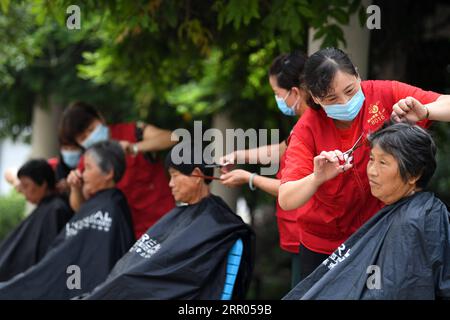 200729 -- HEFEI, July 29, 2020 -- Volunteers cut hair for villagers at a temporary shelter in a school at Feixi County, east China s Anhui Province, July 29, 2020. Affected by floods, over 200 villagers in Fengle Town of Hefei were transferred to the school. Volunteers at the temporary shelter helped with the conveying of flood relief materials, food distribution, health care services, homework tutorship and free hairdressing services.  CHINA-ANHUI-HEFEI-FLOOD-VOLUNTEER CN LiuxJunxi PUBLICATIONxNOTxINxCHN Stock Photo