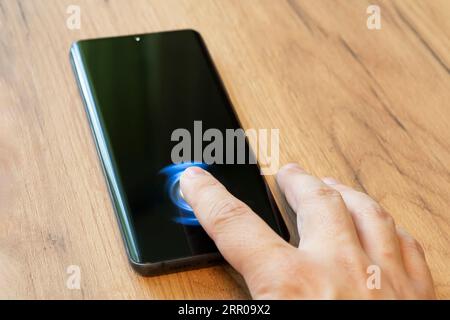 Close up of man using generated mobile smart phone with fingerprint on the screen. Biometric security Stock Photo