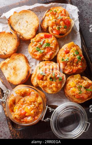 Bread toasts with eggplant caviar closeup on the wooden board on the table. Vertical top view from above Stock Photo