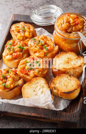 Bread toasts with eggplant caviar closeup on the wooden board on the table. Vertical Stock Photo