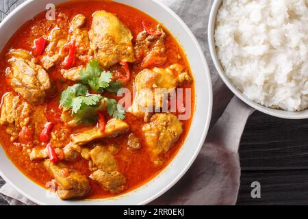 Spicy Burmese chicken curry in a sauce consisting of onion, ginger, lemongrass, pepper, garlic and tomato close-up in a bowl on the table. Horizontal Stock Photo
