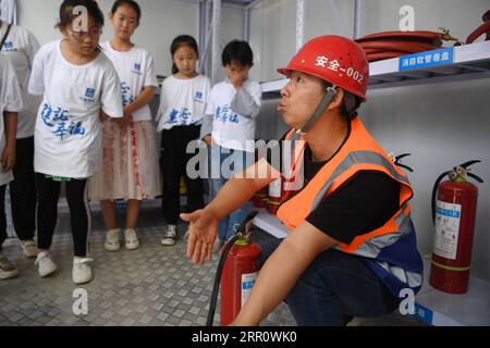 200827 -- LANZHOU, Aug. 27, 2020 -- A staff member of the China Construction Third Engineering Bureau Co., Ltd. introduces safety knowledge to children during a caring activity in Anning District of Lanzhou, northwest China s Gansu Province, Aug. 27, 2020. A caring activity for left-behind children in rural areas was held at a construction site of a women and children s hospital in Lanzhou on Thursday. Experts and volunteers conducted safety knowledge education to children and communicated with parents who are migrant workers here on family education and communication between parents and child Stock Photo