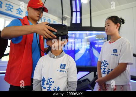 200827 -- LANZHOU, Aug. 27, 2020 -- A child tries out a VR device in Anning District of Lanzhou, northwest China s Gansu Province, Aug. 27, 2020. A caring activity for left-behind children in rural areas was held at a construction site of a women and children s hospital in Lanzhou on Thursday. Experts and volunteers conducted safety knowledge education to children and communicated with parents who are migrant workers here on family education and communication between parents and children.  CHINA-GANSU-LANZHOU-LEFT-BEHIND CHILDREN-SAFETY KNOWLEDGE EDUCATION CN ChenxBin PUBLICATIONxNOTxINxCHN Stock Photo