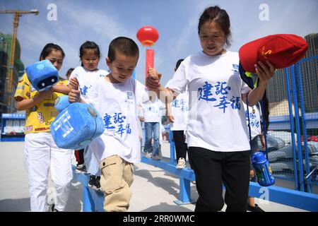 200827 -- LANZHOU, Aug. 27, 2020 -- Parents and children attend a parent-child activity in Anning District of Lanzhou, northwest China s Gansu Province, Aug. 27, 2020. A caring activity for left-behind children in rural areas was held at a construction site of a women and children s hospital in Lanzhou on Thursday. Experts and volunteers conducted safety knowledge education to children and communicated with parents who are migrant workers here on family education and communication between parents and children.  CHINA-GANSU-LANZHOU-LEFT-BEHIND CHILDREN-SAFETY KNOWLEDGE EDUCATION CN ChenxBin PUB Stock Photo