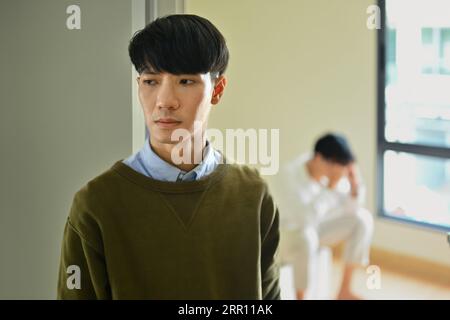 Quarreled gay male couple ignoring each other after quarreling at home. Married problems and conflicts concept Stock Photo